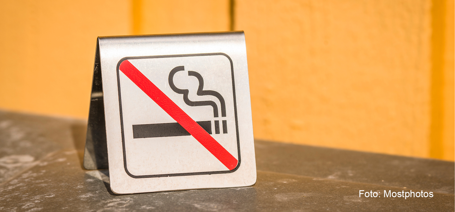 Bilden visar en liten skylt om röknings förbjuden står på ett bord utomhus.